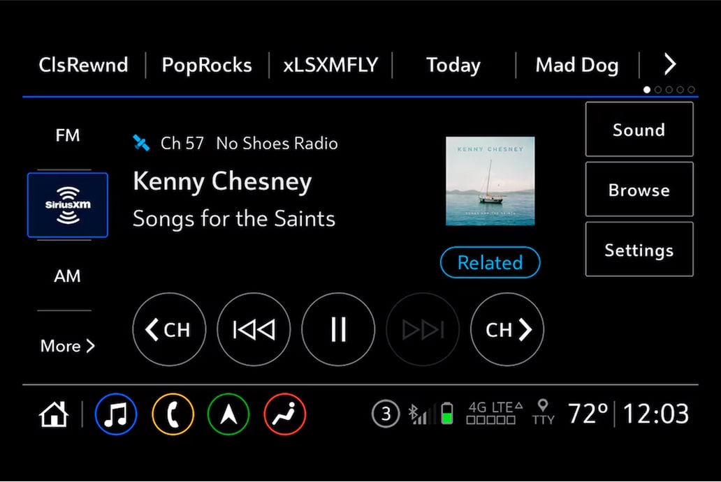 A car's infotainment screen shows SiriusXM playing "Songs for the Saints" by Kenny Chesney, featuring album art of a sailboat.