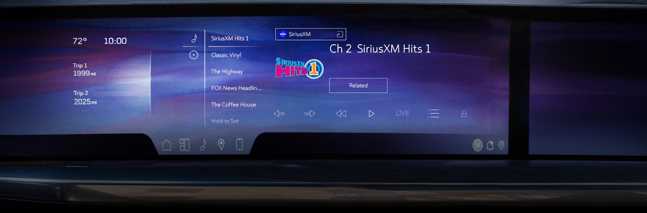 A wide shot of a car's dashboard highlights the infotainment screen displaying the SiriusXM Hits 1 channel playing music.