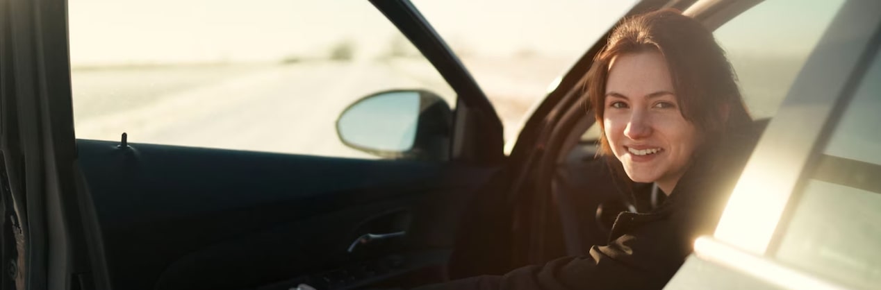 A young girl smiling as she steps out of her vehicle