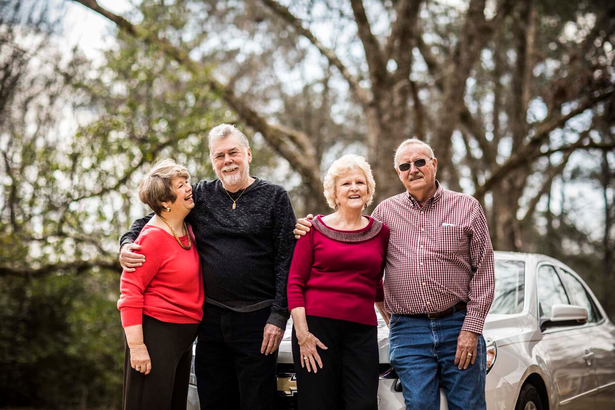 Two Elderly Couples Standing in Front of Vehicle