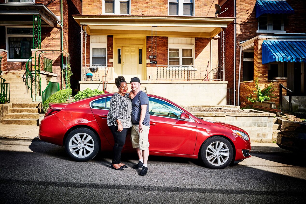 Couple Standing by GM Vehicle Parked in Front of Apartment