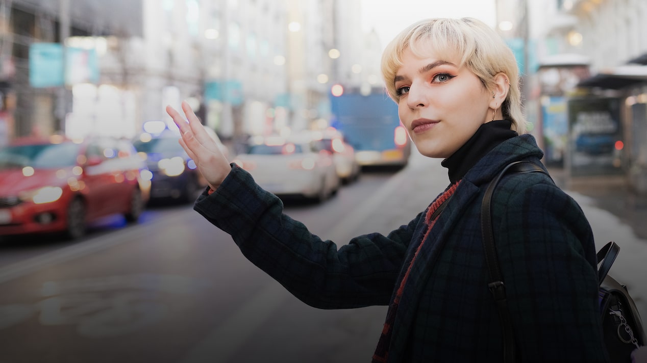 Woman With Blonde Hair Waving Down a Taxi on a City Street