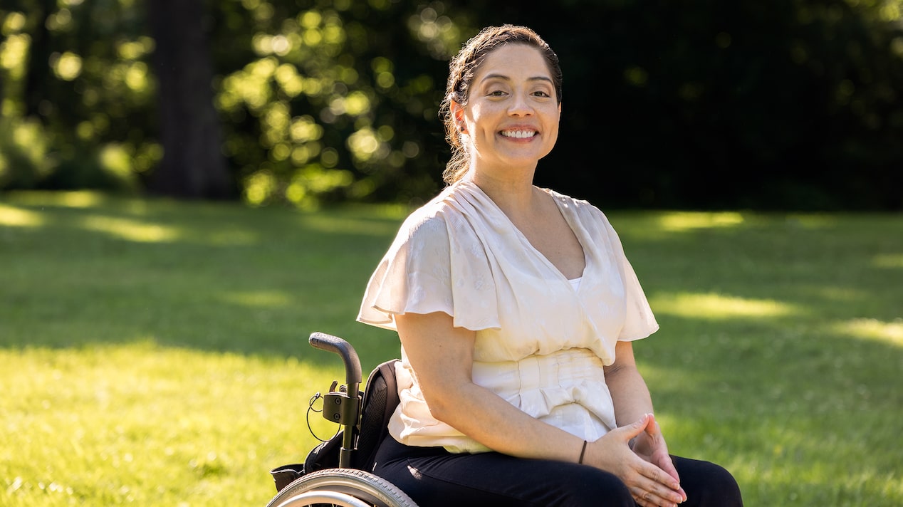 A Woman in a Wheelchair Wearing White Smiling at the Camera