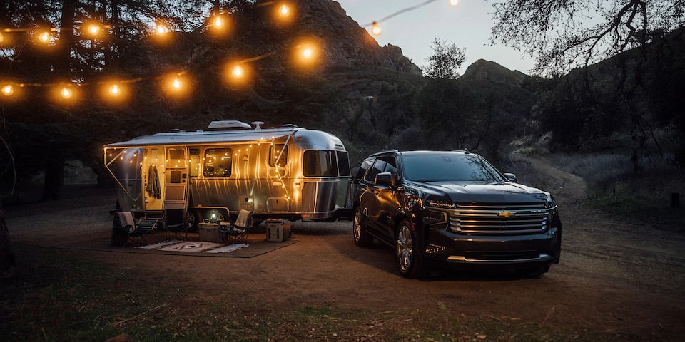 Chevy Vehicle Parked in Woods at Night with Camper Attached