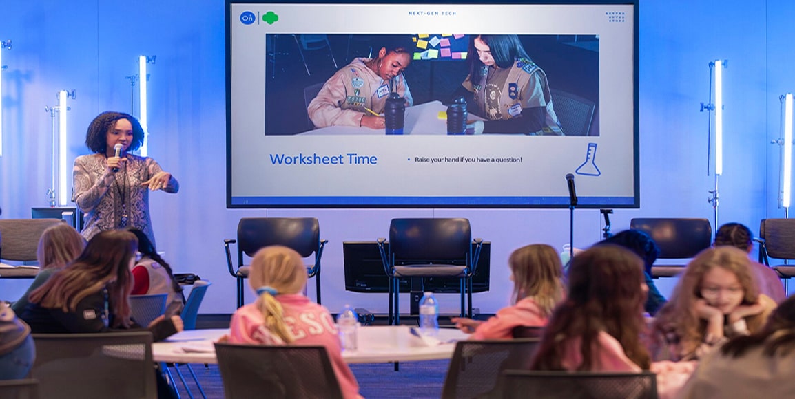 A woman leader presents to Girl Scouts during an OnStar STEAM educational conference.