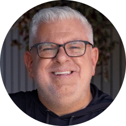 A close-up portrait of Jason Cupp, a middle-aged man with gray hair and glasses, smiling broadly.