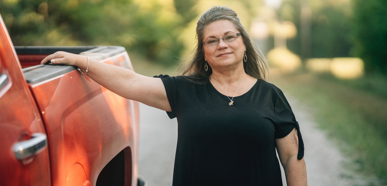 Woman Smiling With Her Arm Laid On the Bed of a GM Truck