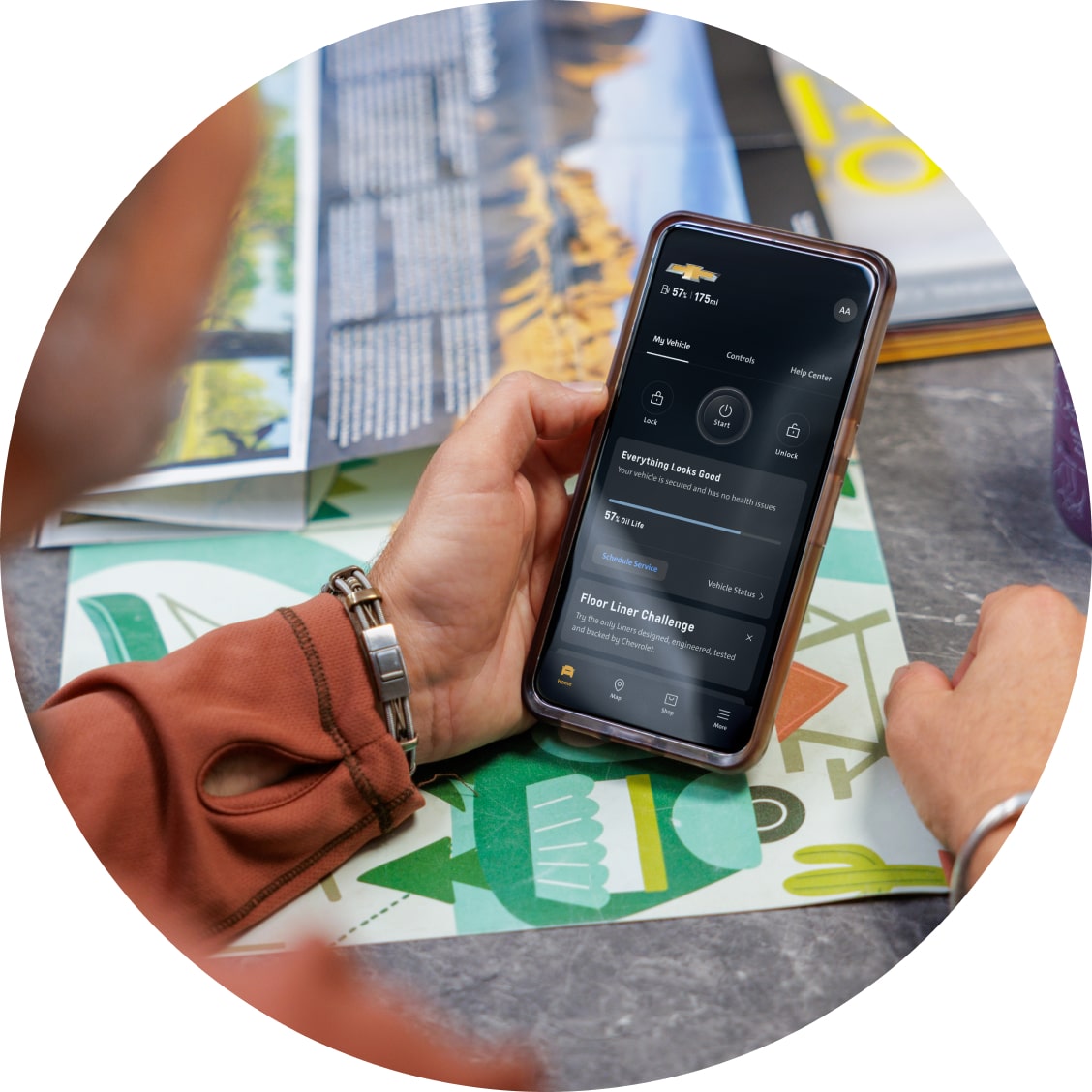 A bird's eye view of a man looking at the OnStar app on his smartphone.