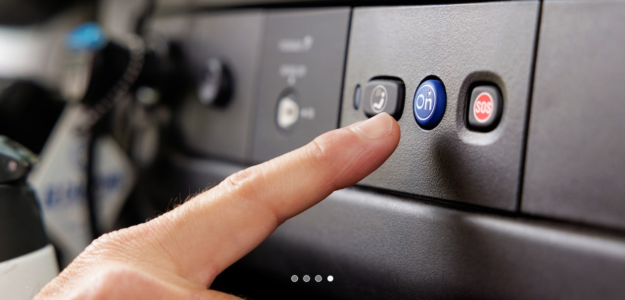 A person's finger pressing the OnStar button in their vehicle.