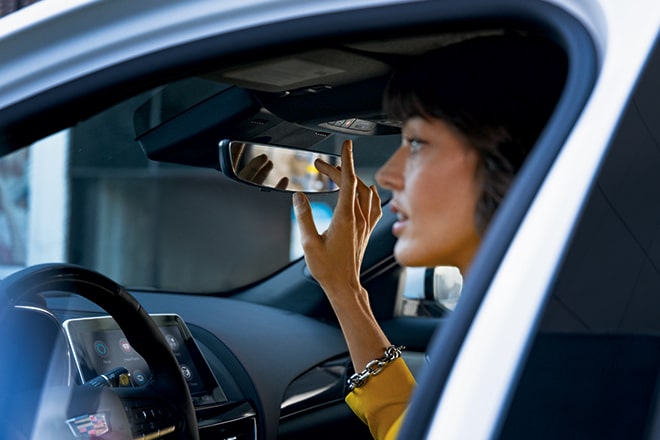 A Woman Driver Pressing the OnStar Button on Rear View Mirror