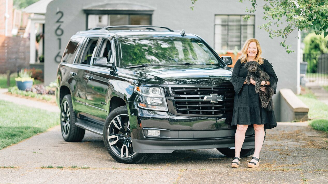 Woman With a Black Dog Standing in Front of her Chevy SUV