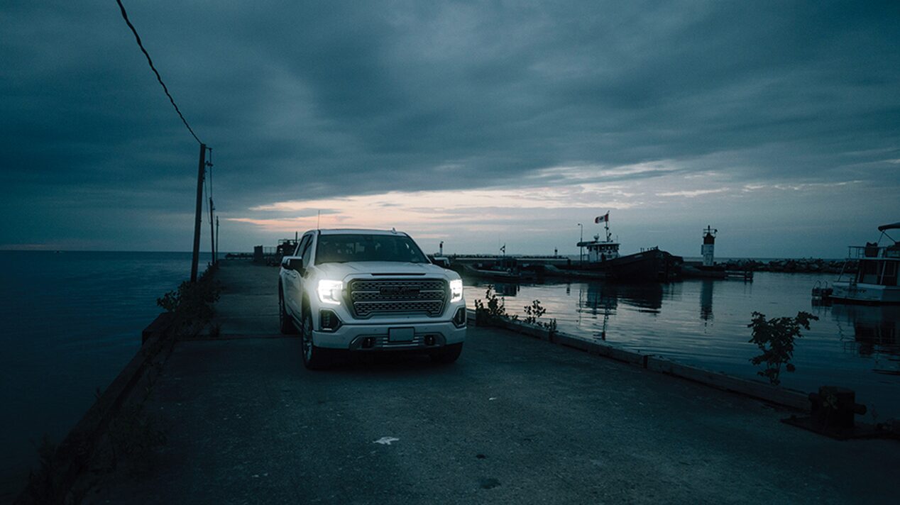 White GMC Truck on a Paved Road with Water on Either Side
