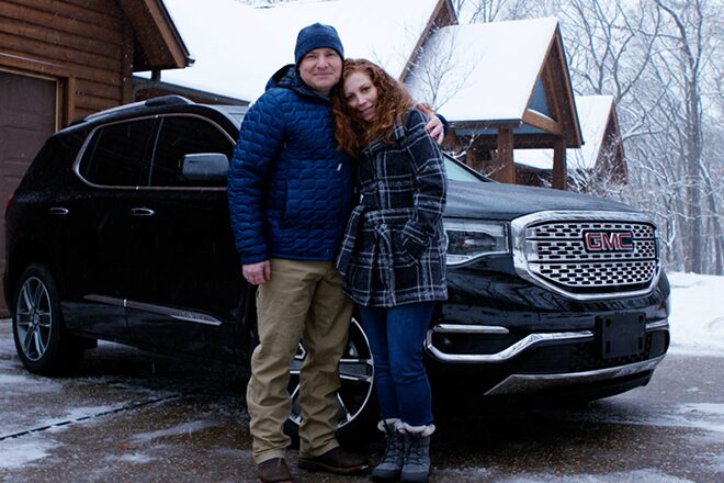 Couple Stands During Winter in Front of their GMC Acadia