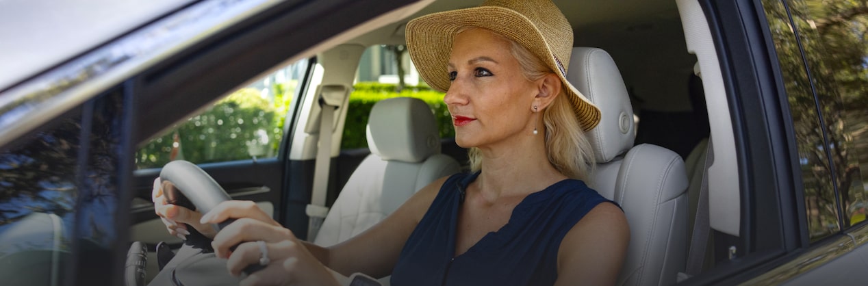 A woman driving in a vehicle seen from outside the window 