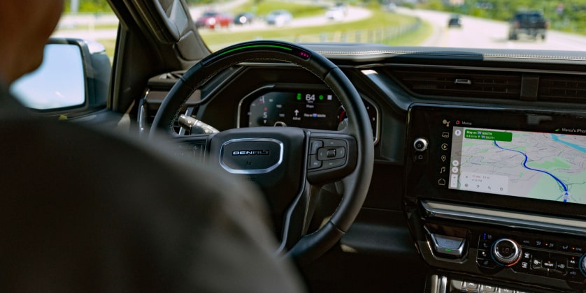 A view of the front dashboard and steering wheel with a man in the driver's seat