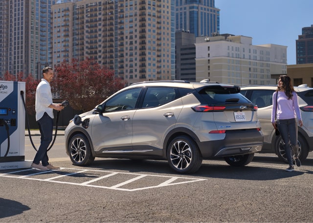A man using a public charging station for his GM electric vehicle