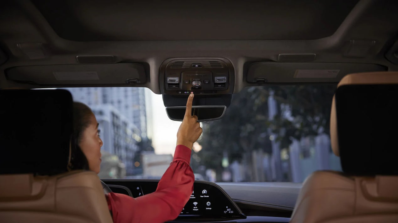 Backseat View of Driver Pressing the OnStar Button While in the City