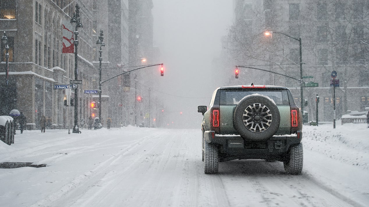 Hummer EV Driving Through a Snowy City Road
