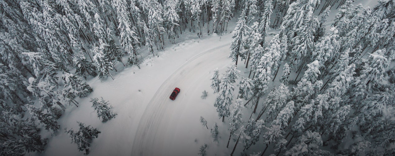 Birds Eye View of Vehicle Driving Through Snowy Forest