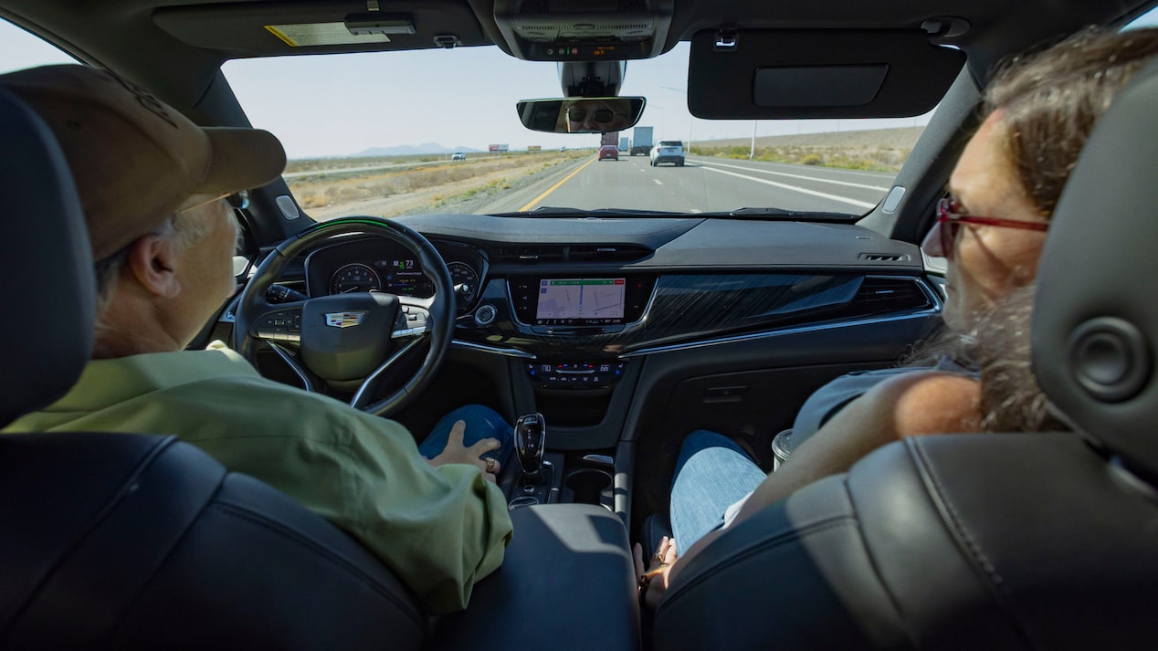Andrew K. and Sue K. are seen from the back seat, riding in their Cadillac XT6 on a highway.