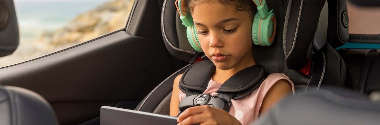 Little Girl in Car Seat Using iPad with Headphones