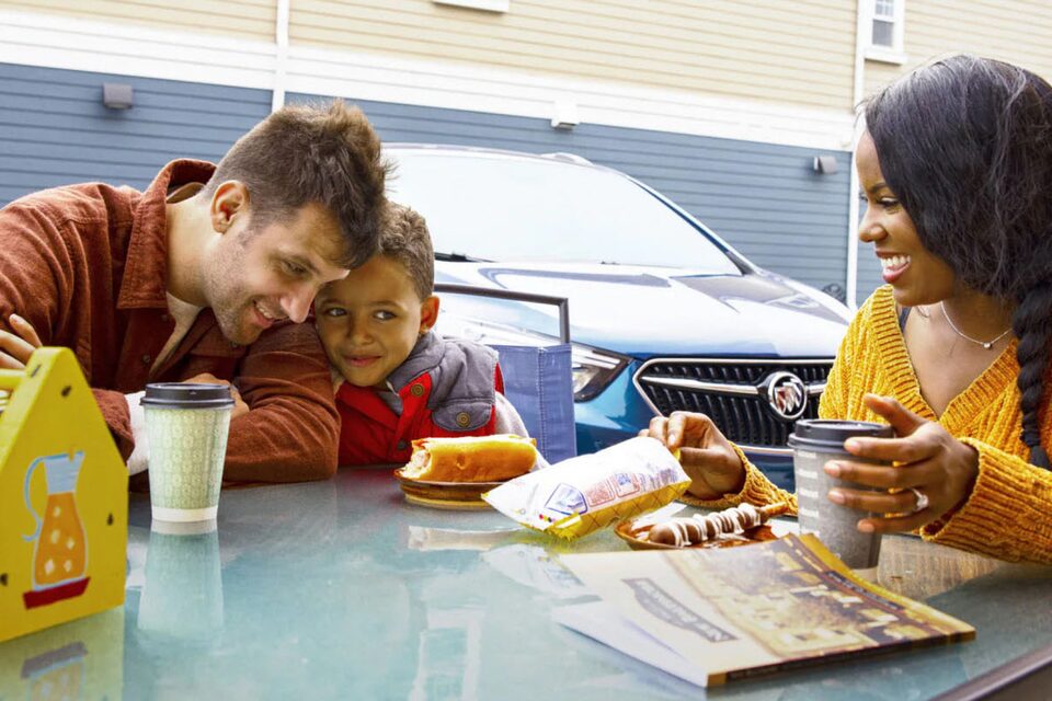 Family of Three Sitting at Rest Stop Table on Road Trip
