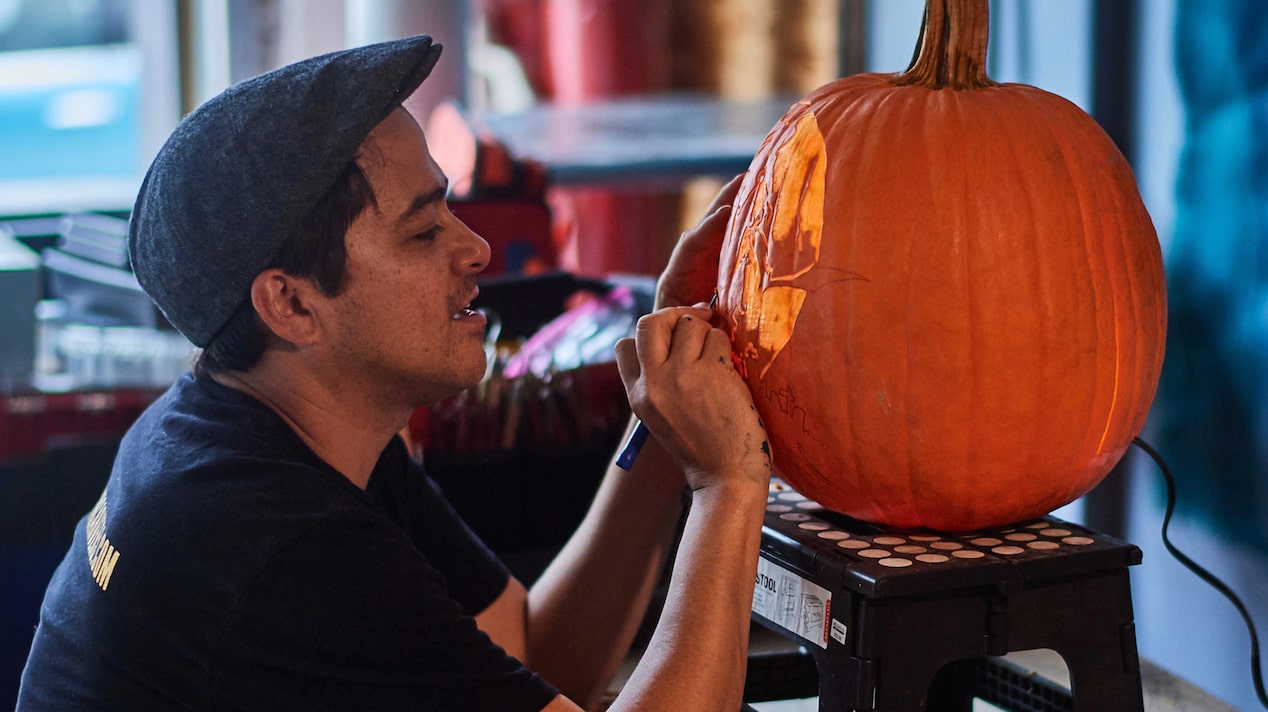 Man Carving and Painting a Pumpkin