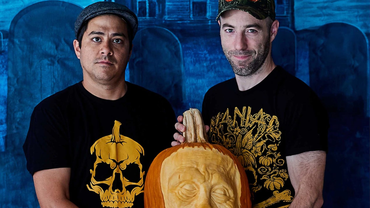 Two Men Holding Up Carved Pumpkins