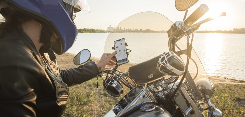 Motorcycle Driver Parked by the River and Checking the OnStar Guardian App