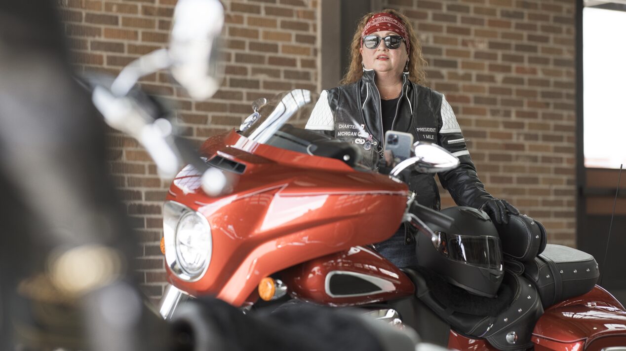 Woman Motorcyclist Wearing a Red Bandana Stranding Next to Her Bike