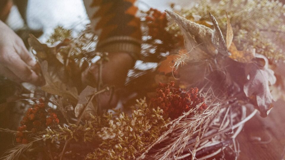 Woman Using Foraged Items to Add Detail on the Wreath