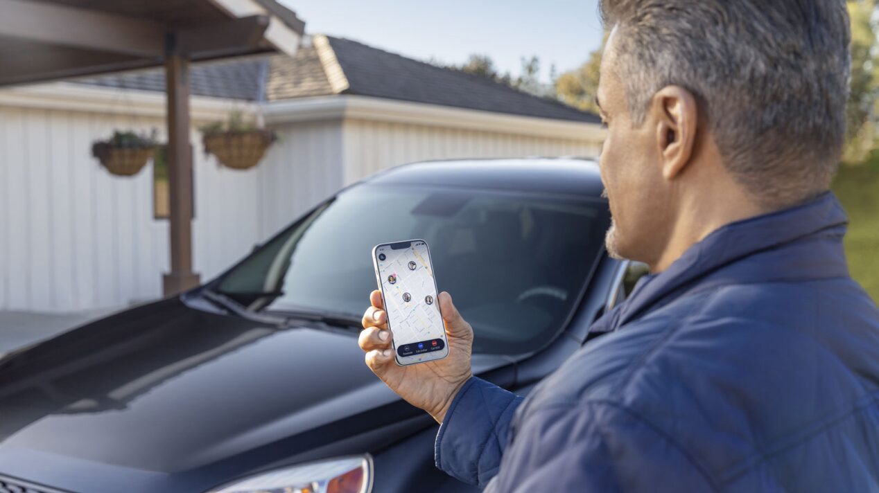 Man Looking At the Guardian App In Front of His Vehicle