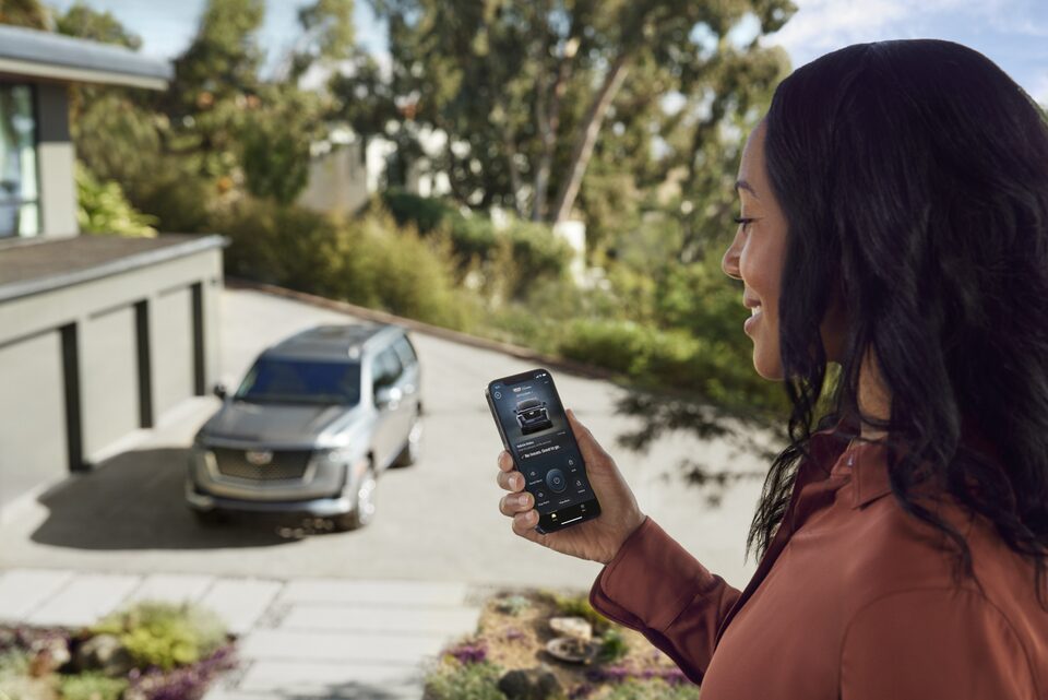 Women Using Smartphone While Looking out at Vehicle Parked in Driveway