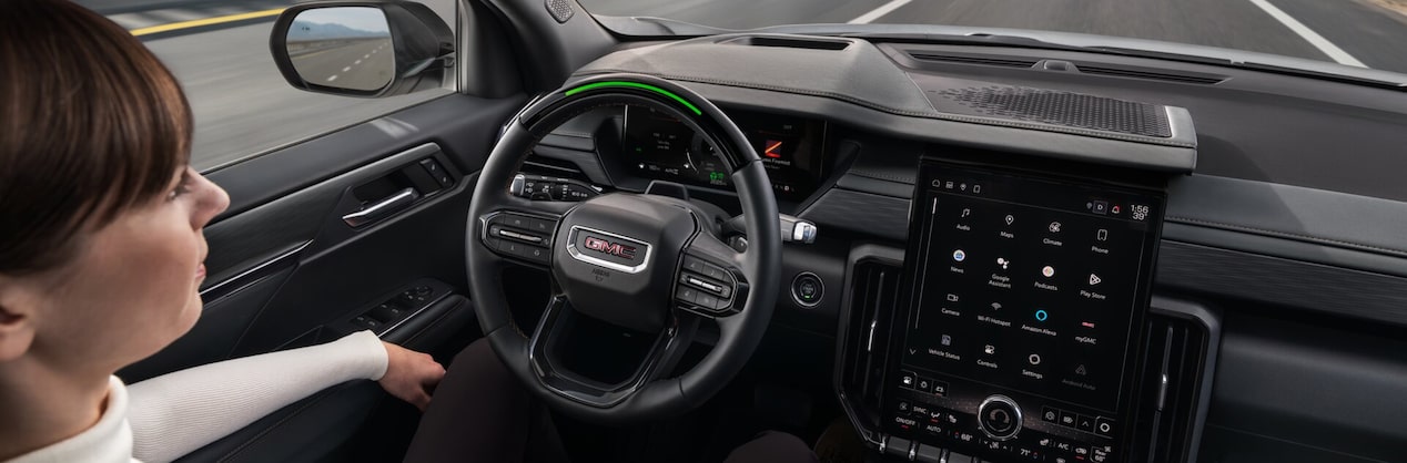 A couple driving down the road using Super Cruise hands-free driving assistance technology