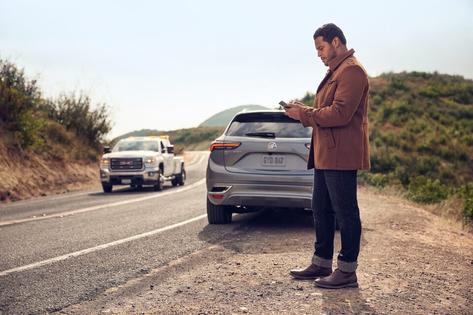 Man on the Side of the Road Glancing at Phone Behind Buick