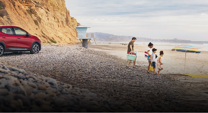A family arriving at the beach with their GM vehicle parked in the background